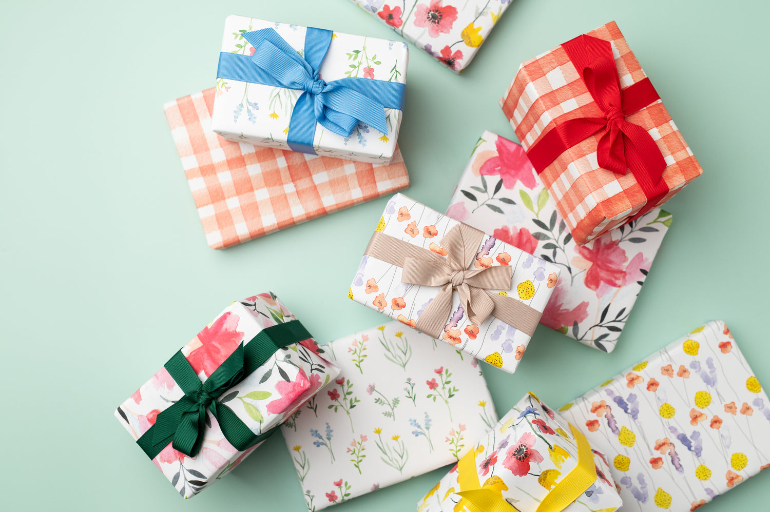An image of various presents wrapped in Ruby &amp; Bo Recycled Wrapping Paper on a mint green background