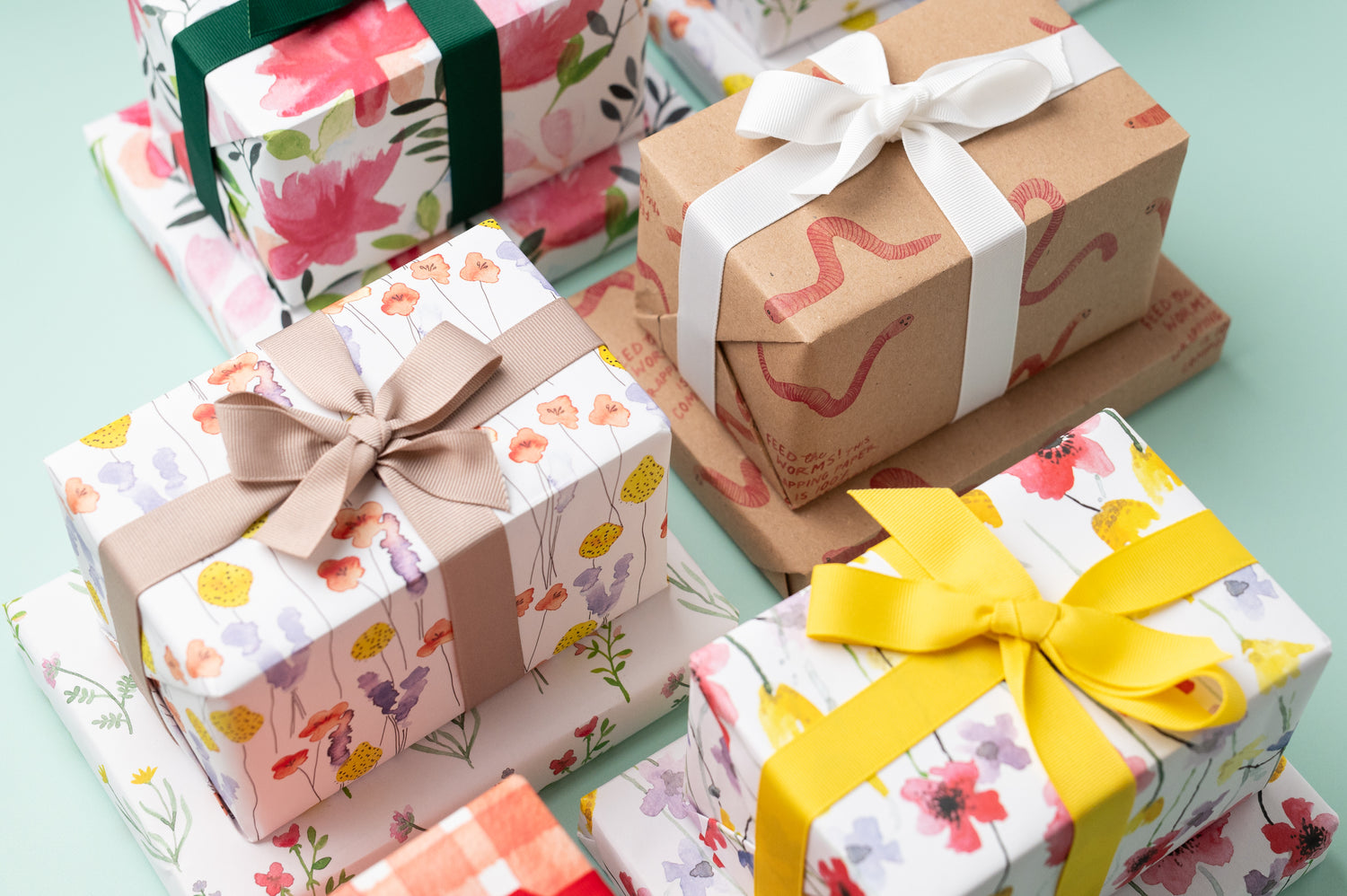 A selection of presents wrapped in Ruby &amp; Bo recycled wrapping paper on a mint green background
