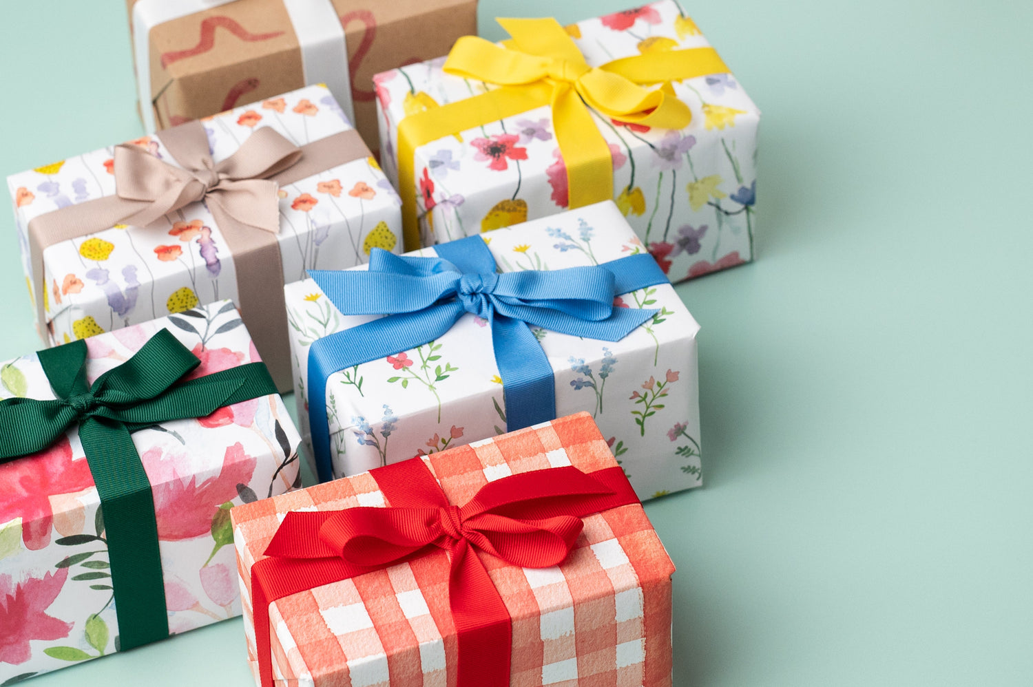 A selection of presents wrapped in Ruby &amp; Bo Recycled Wrapping Paper on a mint green background