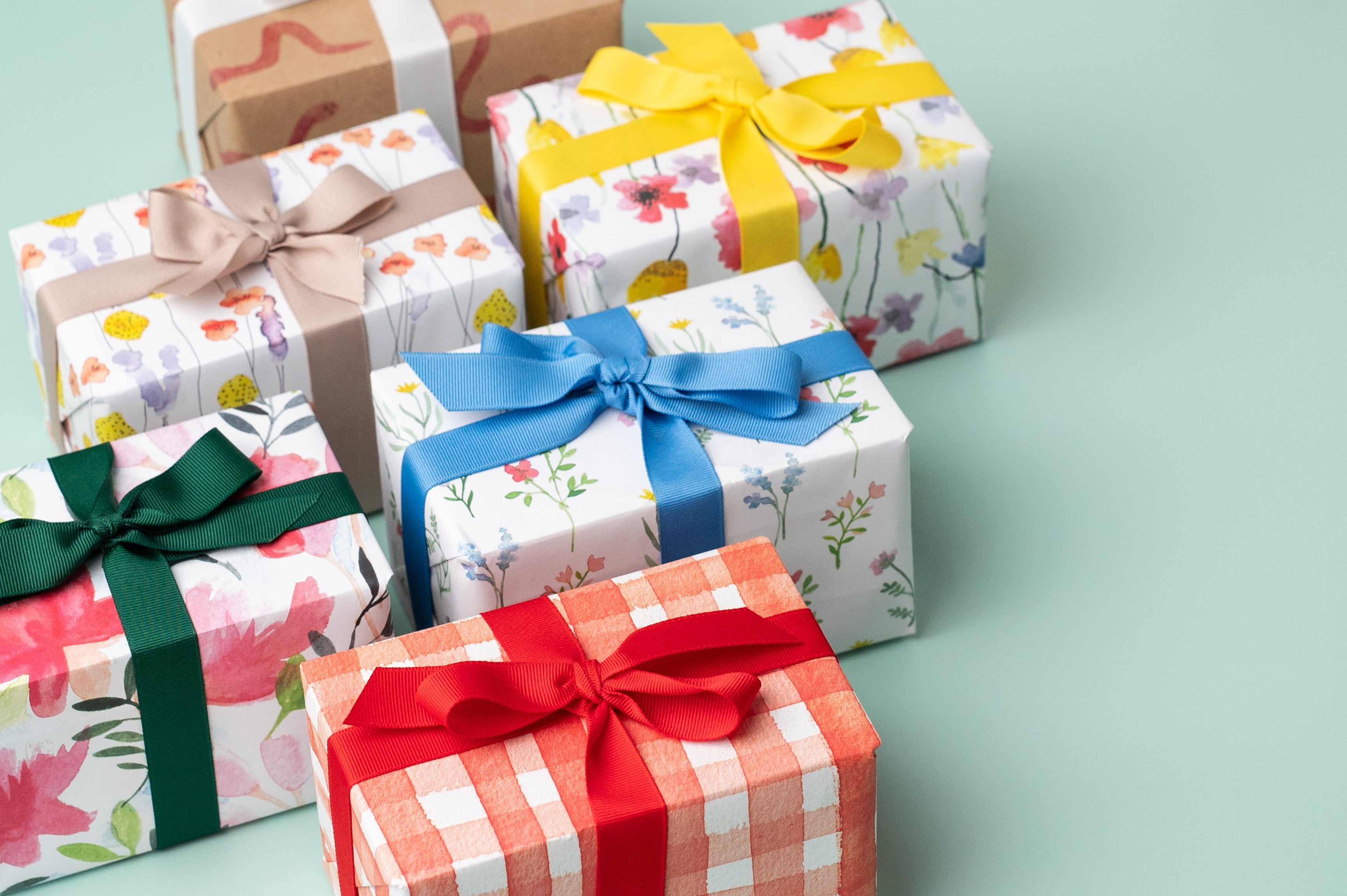 A selection of presents wrapped in Ruby & Bo Recycled Wrapping Paper on a mint green background