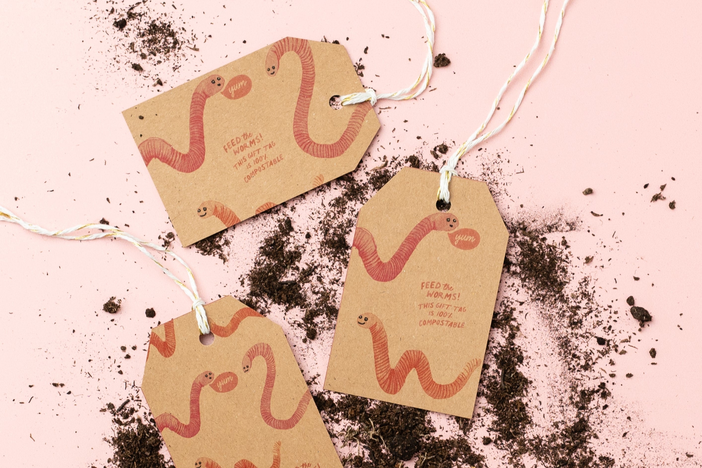 Ruby & Bo kraft paper gift tags on a pale pink background with a scattering of compost