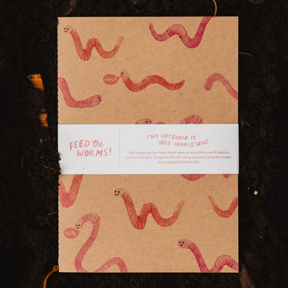 Feed the Worms 100% Compostable Notebook on pile of compost