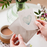 image of ruby & bo plantable blue heart notecard being taken out of grey envelope
